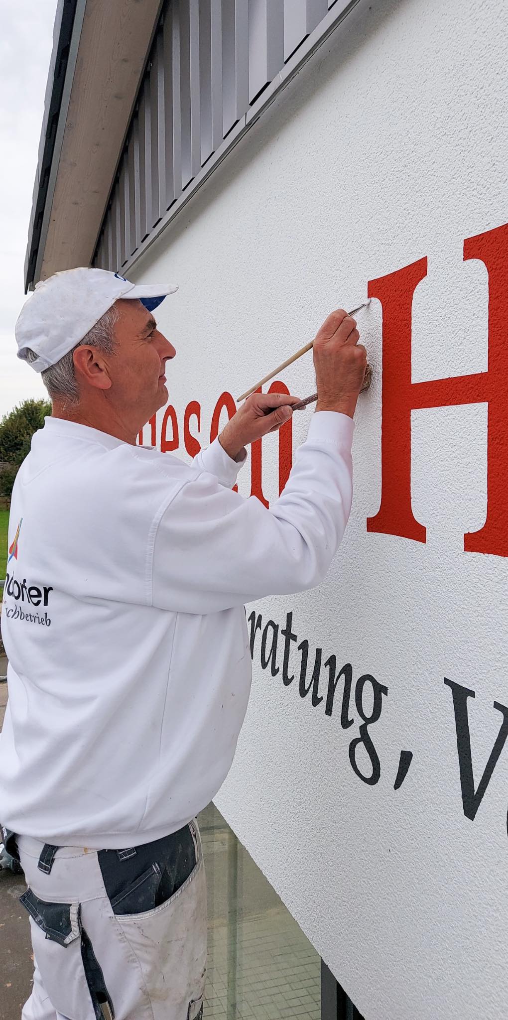 Facharbeiter beim Aufmalen einer Beschriftung auf eine Fassade nach Kundenwunsch in Hilpoltstein